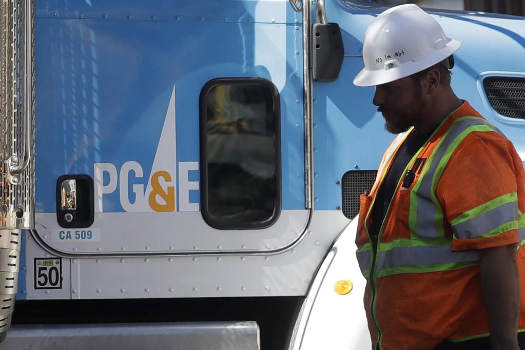 FILE -- In this Aug. 15,2019 file photo a Pacific Gas & Electric worker walks in front of a truck in San Francisco. (AP Photo/Jeff Chiu, File)