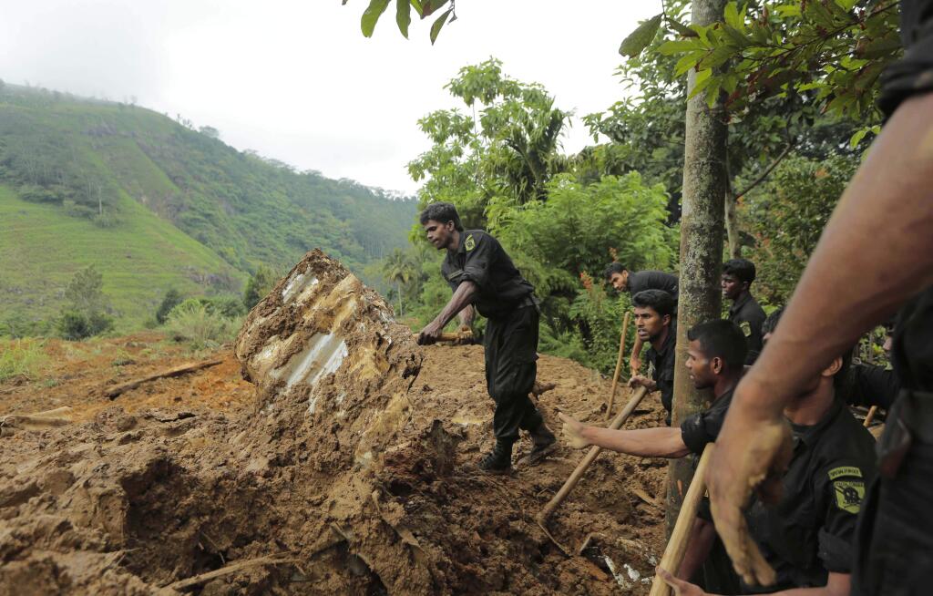 Sri Lankan army soldiers clear debris as they help in rescue operations at the site of a mudslide at the Koslanda tea plantation in Badulla district, about 220 kilometers (140 miles) east of Colombo, Thursday, Oct. 30, 2014. Disaster Management Minister Mahinda Amaraweera estimated the number of dead in Wednesday's disaster would be fewer than 100, although villagers said the figure could easily exceed 200. (AP Photo/Eranga Jayawardena)