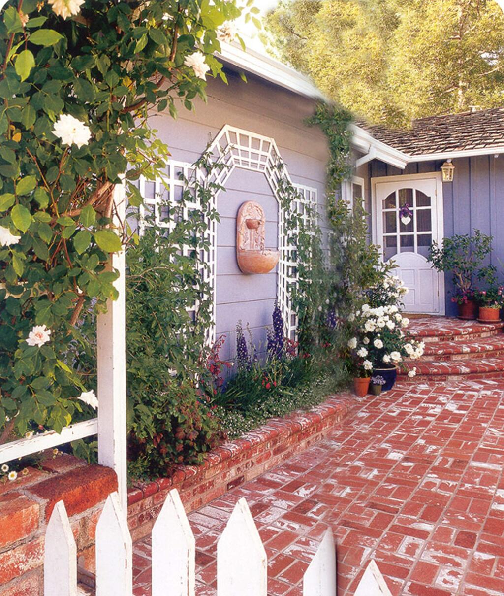 This home's entrance was transformed from a boring, unadorned walk into an interesting garden by adding wall decorations to the side of the house .Borrowed from the French, this trellising technique called “tromp l'oeli” (meaning 'fool the eye') gives the false impression of a larger, three dimensional space. The fountain in the middle as a focal point adds a sweet sound of trickling water and the whole space is soothing and welcoming. (Louise Leff)