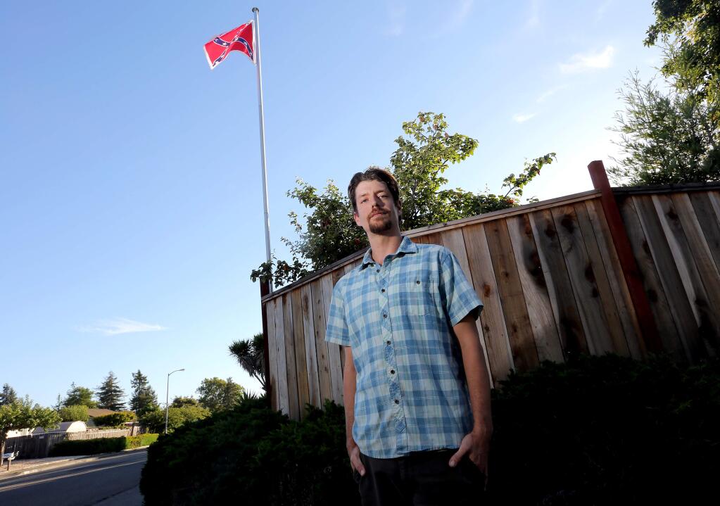 Travis Kilbourne, a civil war re-enactor stands next to the fence of his home he rents from his parents where he put up a 'Battle Flag,' Wednesday, June 24, 2015. (Crista Jeremiason/ The Press Democrat)