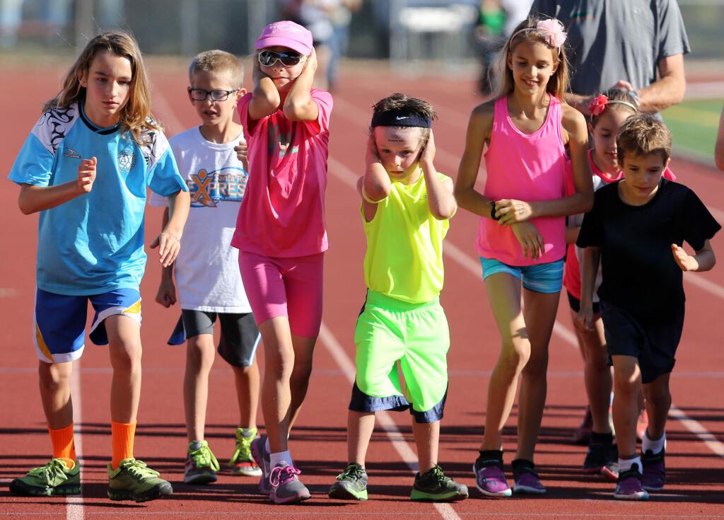 Lexi Jones, 9, third from left and George Martin, 5, fourth from left, hold their ears as the gun goes off for the start of the 1600 meter run during the Empire Runners' Summer Track Series held at Santa Rosa High School, Tuesday, June 23, 2015. (CRISTA JEREMIASON / The Press Democrat)