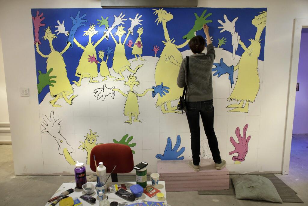 In this May 4, 2017 photo Cortney Thibodeau, a senior at University of Massachusetts at Amherst, paints a mural based on artwork from the Dr. Seuss book 'Oh, The Thinks You Can Think!' at The Amazing World of Dr. Seuss Museum, in Springfield, Mass. The museum devoted to Dr. Seuss, which opened on June 3 in his hometown, features interactive exhibits, a collection of personal belongings and explains how the childhood experiences of the man, whose real name is Theodor Geisel, shaped his work. (AP Photo/Steven Senne)