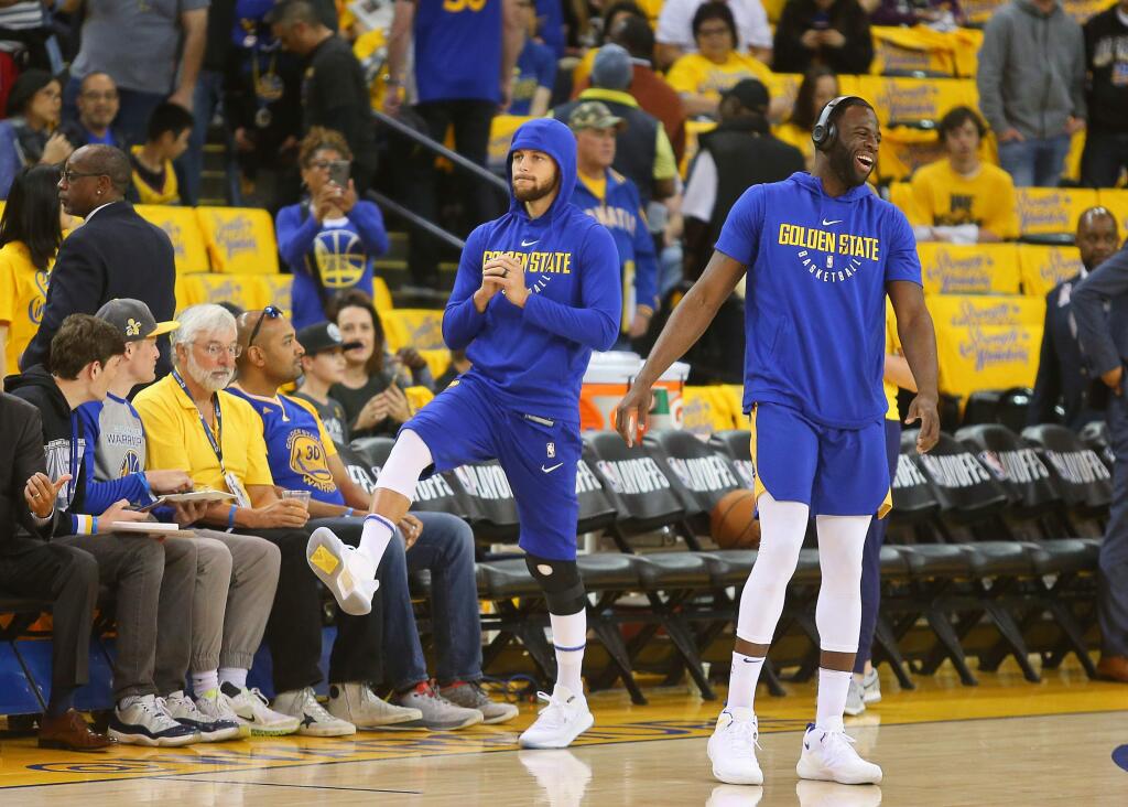 Warriors guard Stephen Curry goes through exercises while Draymond Green warms up before Game 1 against the San Antonio Spurs, in Oakland on Saturday, April 14, 2018. (Christopher Chung / The Press Democrat)