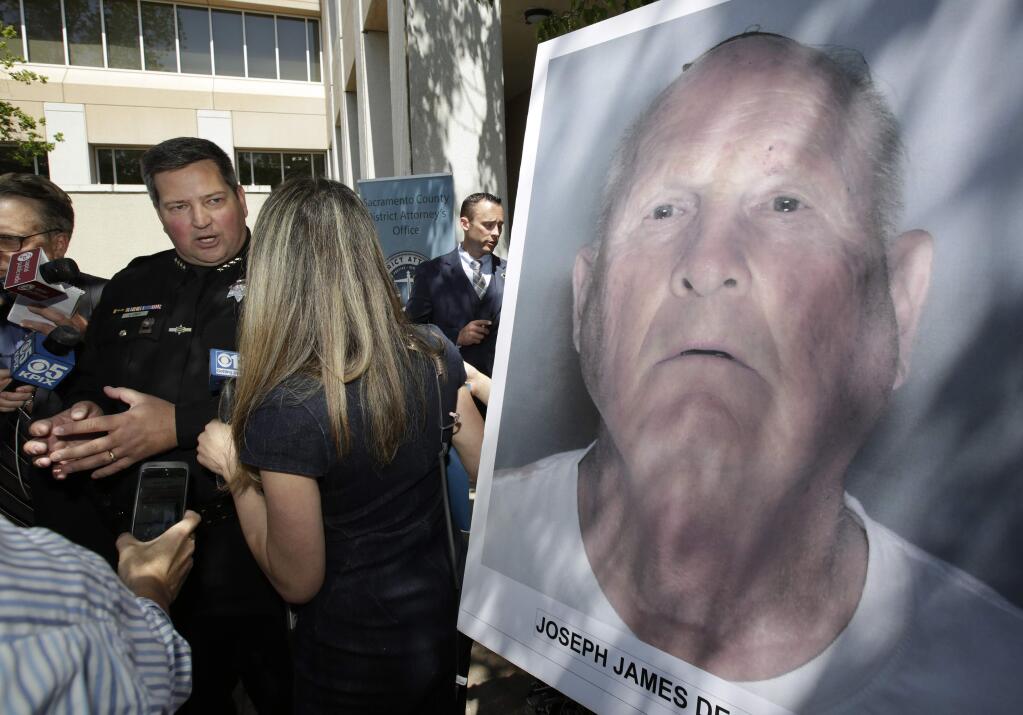 Sacramento County Sheriff Scott Jones, left, talks to reporters about the arrest Joesph James DeAngelo, seen in photo, on suspicion of committing a string of violent crimes in the 1970's and 1980's after a news conference. Wednesday, April 25, 2018, in Sacramento, Calif. A DNA match led to the arrest of DeAngelo, 72, Tuesday. DeAngelo is believed to have committed at least 12 slayings and 45 rapes in California.(AP Photo/Rich Pedroncelli)