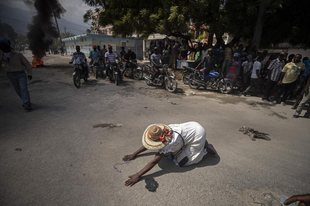A churchgoer drops to the ground and prays in the street near burning tires lit by protesters, during a march called by religious leaders in Port-au-Prince, Haiti, Oct. 22, 2019. The image was part of a series of photographs by Associated Press photographers which was named a finalist for the 2020 Pulitzer Prize for Breaking News Photography. (AP Photo/Rebecca Blackwell)