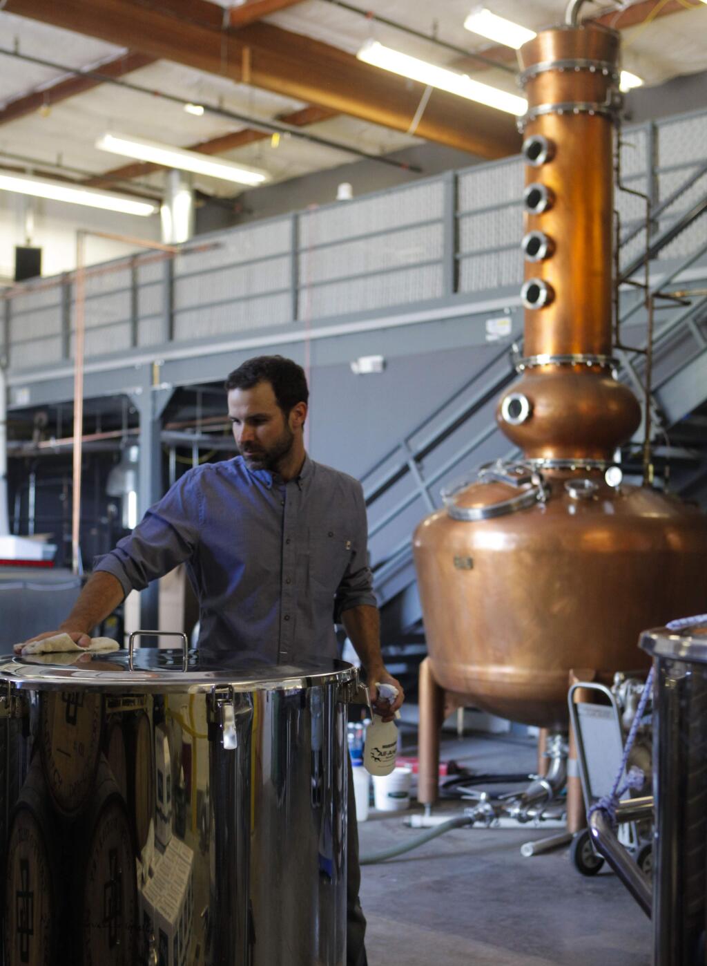 Petaluma, CA, USA. Tuesday, August 16, 2016._ Michael Griffo, owner of Griffo Distillery cleans up equipment in their distillery where they recently opened an adjoining tasting room. Behind him is a copper still where he is currently making whiskey. (CRISSY PASCUAL/ARGUS-COURIER STAFF)