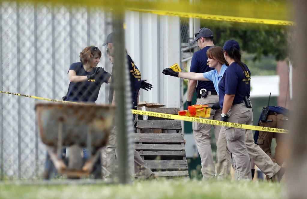 Investigators hand off an evidence flag around the baseball field in Alexandria, Va., Wednesday, June 14, 2017, that was the scene of a shooting where House Majority Whip Steve Scalise of La., and others, were was shot during a congressional baseball practice. (AP Photo/Alex Brandon)
