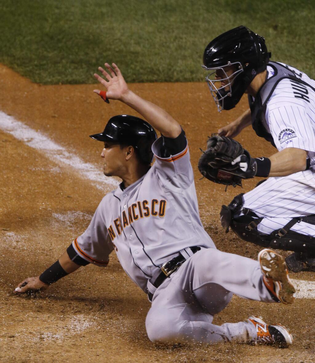 San Francisco Giants' Nori Aoki, left, slides safely across home plate with the go-ahead run next to Colorado Rockies catcher Nick Hundley (4) during the 11th inning of a game Saturday, April 25, 2015, in Denver. The Giants won 5-4 in 11 innings. (AP Photo/David Zalubowski)