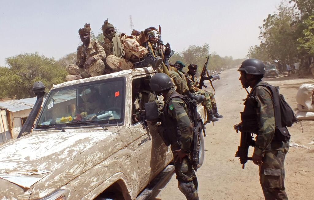 In this photo taken on Thursday, Feb. 19, 2015, Chadian soldiers on top of a truck, left, speak to Cameroon soldiers, right, standing next to the truck, on the border between Cameroon and Nigeria as they form part of the force to combat regional Islamic extremists force's including Boko Haram, near the town of Fotokol, Cameroon. A girl suicide bomber as young as 10 blew herself up at a busy market in the northeastern Nigerian town of Potiskum on Sunday, Feb. 22, 2015, killing four others and seriously wounding 46 people, a witness and hospital records show. (AP Photo/Edwin Kindzeka Moki)