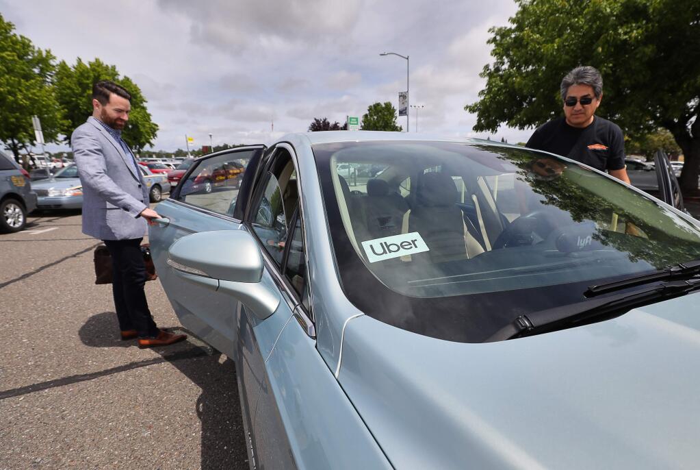 Michael Brownfield, left, is picked up by Rolando Vera, who drives for both Lyft and Uber, at the Charles M. Schulz-Sonoma County Airport in Santa Rosa on Monday, May 20, 2019. Uber began formal service at the airport Monday, while Lyft has been providing service there for the past three years.(Christopher Chung/ The Press Democrat)
