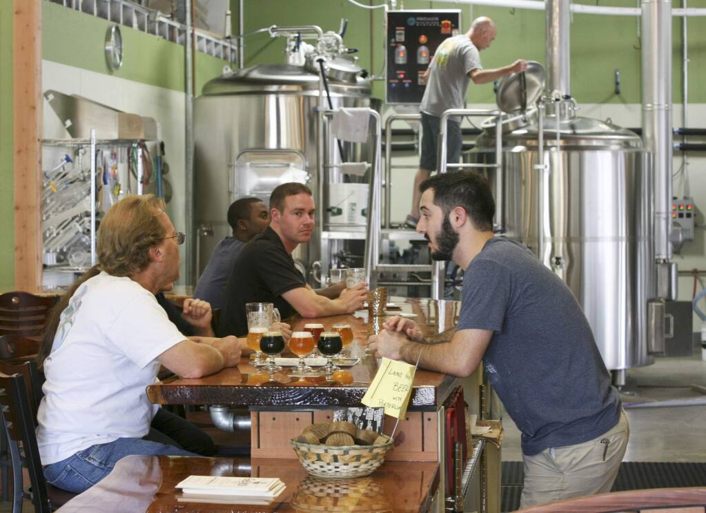 Austin Jay chats with Gardner Hawkins of Guerneville while his dad JJ Jay brews in the background at Petaluma Hills Brewing Co. in Petaluma in 2014. (SCOTT MANCHESTER / ARGUS-COURIER STAFF)