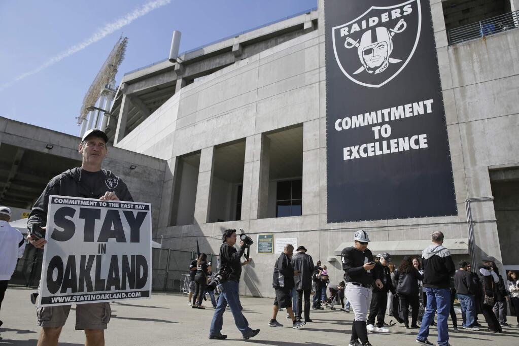John P. Kelleher holds up a sign outside the Oakland Coliseum before the start of a rally to keep the Oakland Raiders from moving Saturday, March 25, 2017, in Oakland. (AP Photo/Eric Risberg)