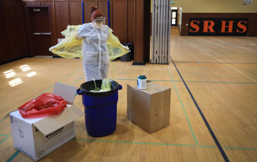 LVN Ana McCoy, who drove up from the Bay Area, sheds protective gear after administering coronavirus tests to whoever wanted one Tuesday, May 5, 2020 at Santa Rosa High School. The testing was done through a company called OptumServe and was by appointment only. (Kent Porter / The Press Democrat) 2020