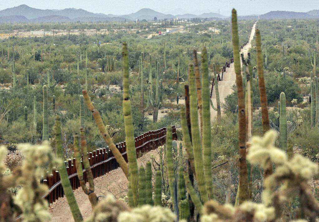 FILE - This Feb. 17, 2006 file photo shows a fence separating Organ Pipe Cactus National Monument, right, and Sonyota, Mexico, running through Lukeville, Ariz. The federal government plans on replacing barriers through 100 miles of the southern border in California and Arizona, including through a this national monument and a wildlife refuge, according to government documents and environmental advocates. The Department of Homeland Security on Tuesday waived environmental and dozens of other laws to build more barriers along the southern border. (AP Photo/Matt York, File)