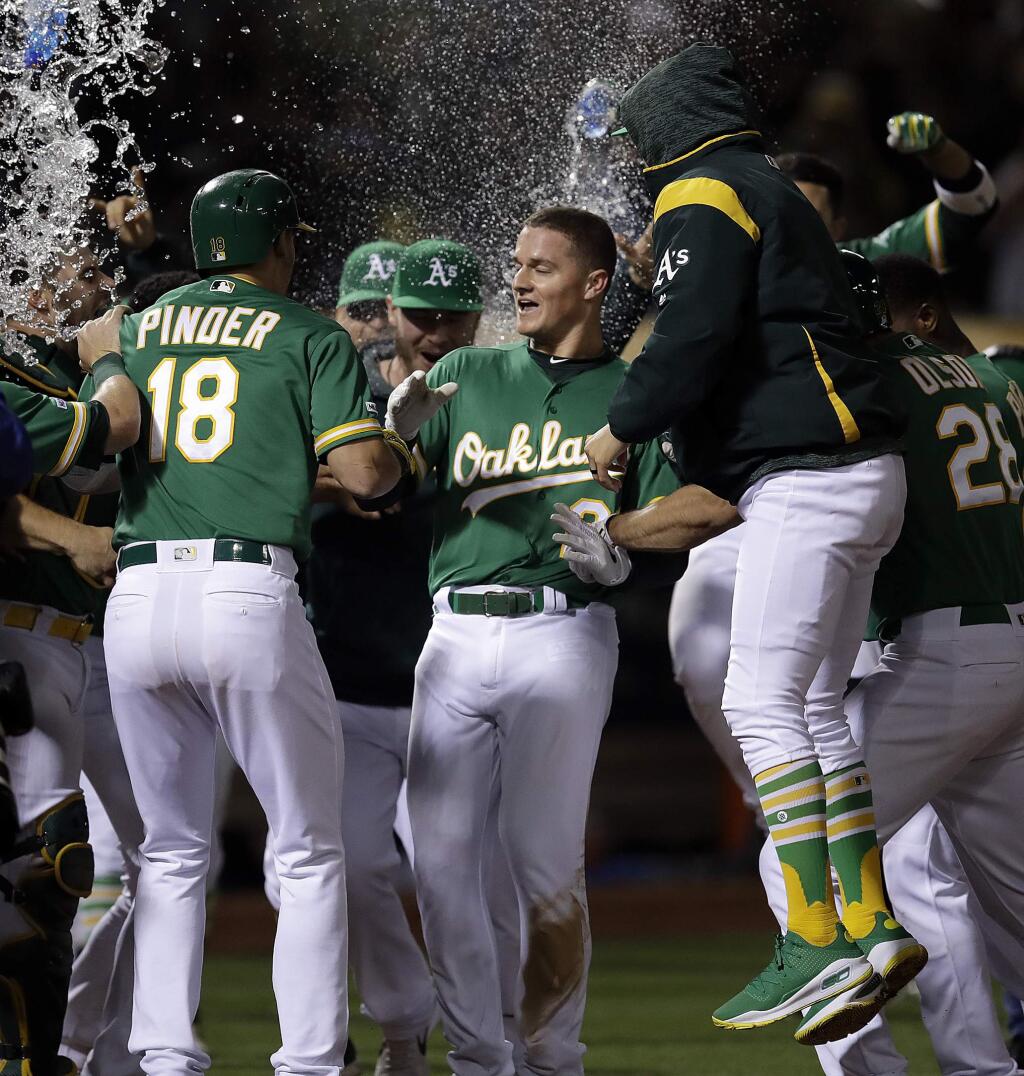 Oakland Athletics' Matt Chapman, center, celebrates after hitting a game-winning home run against the Cleveland Indians in the 12th inning of a baseball game Friday, May 10, 2019, in Oakland, Calif. (AP Photo/Ben Margot)
