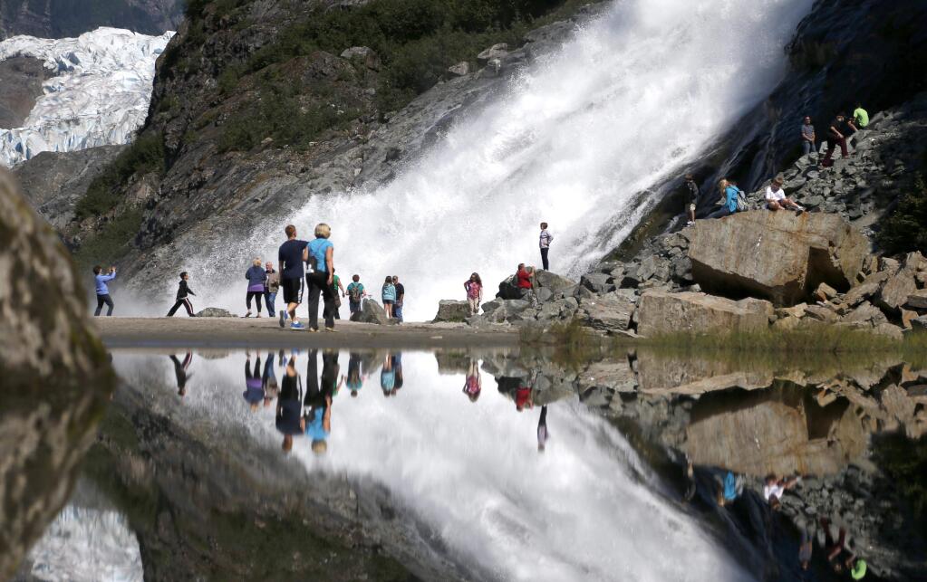 Tourist at the Mendenhall Glacier in the Tongass National Forest are reflected in a pool of water as they make their way to Nuggett Falls Wednesday, July 31, 2013, in Juneau, Alaska (AP Photo/Charles Rex Arbogast)
