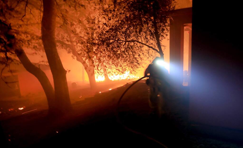Cal Fire firefighters protect a structure at 1108 Bennett Lane and Highway 128 in Napa County close to the origin of the Tubbs fire, Sunday Oct. 8, 2017. The house later burned to the ground. The home was among the first to catch fire. (Kent Porter / Press Democrat) 2017