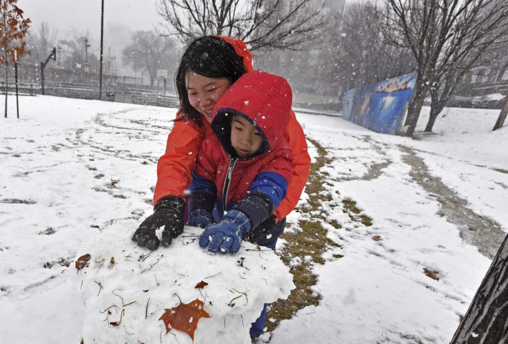 Jinchun Xia, left, and Kevin Liu, 5, of San Francisco, roll a ball of snow for a snowman they made at Wingfield Park in downtown Reno, Nev., Friday, Feb. 15, 2019. (Andy Barron/The Reno Gazette-Journal via AP)