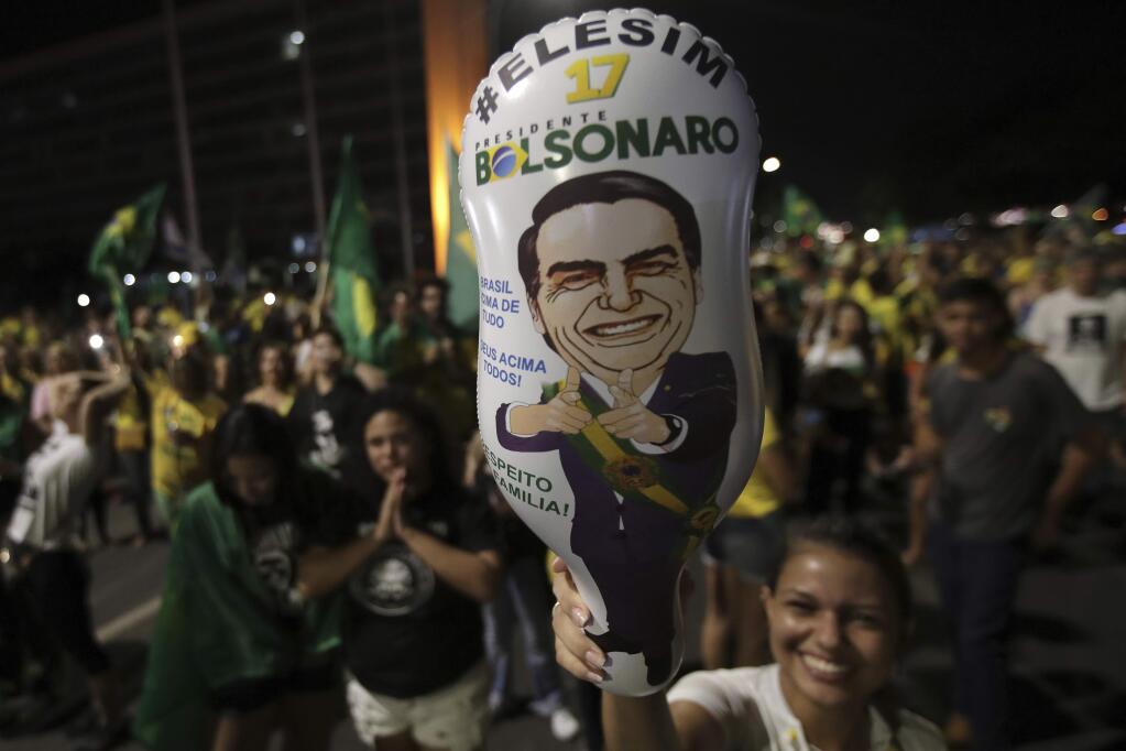 A supporter holds a balloon with the image of presidential candidate Jair Bolsonaro, during celebration in front of the National Congress, in Brasilia, Brazil, Sunday, Oct. 28, 2018. Brazil's Supreme Electoral Tribunal declared the far-right congressman the next president of Latin America's biggest country. (AP Photo/Eraldo Peres)