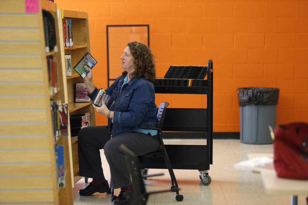 Kathy DeWeese, the coordinator of Children's Services for the Sonoma County Library System, puts DVDs on the shelves before the Roseland Community Library opened in 2015. (BETH SCHLANKER / The Press Democrat)