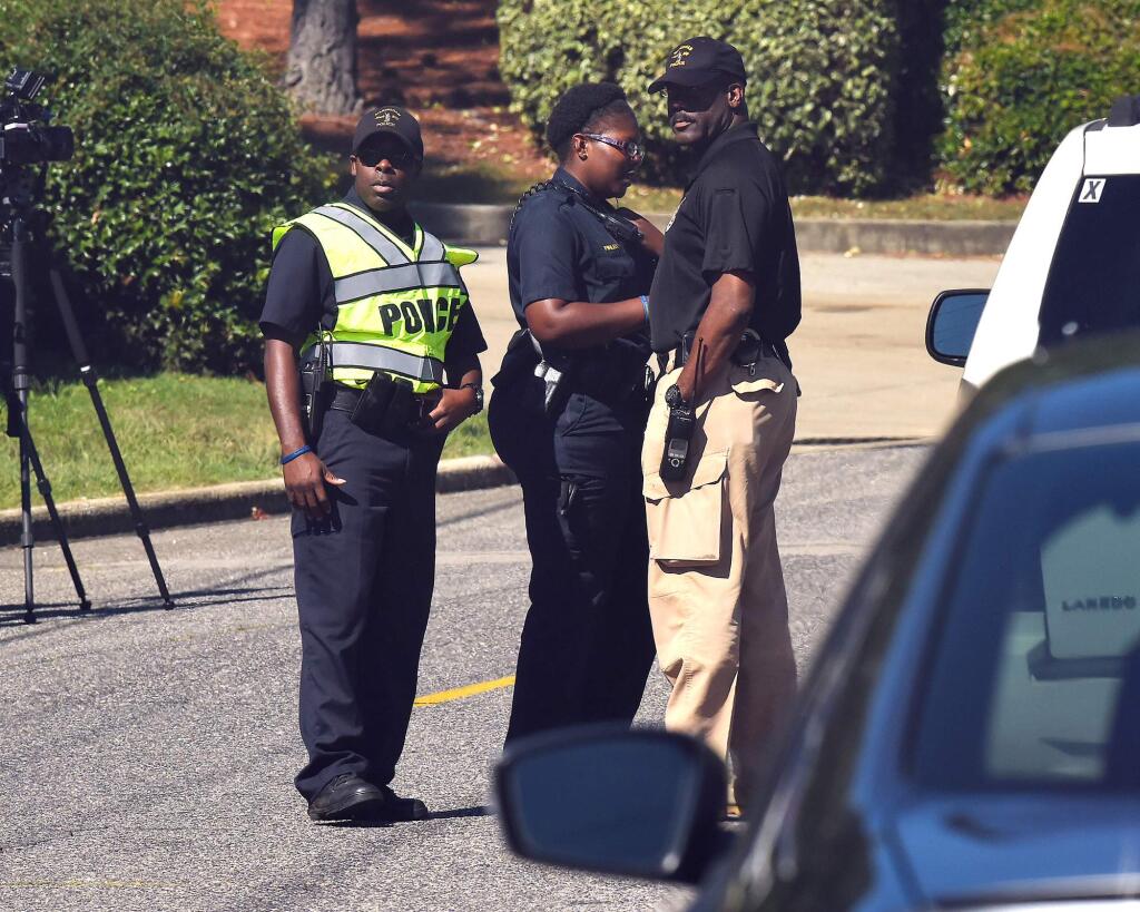 Police officers confer near the scene where three people were killed, including the gunman, at a UPS facility in Birmingham, Ala., Tuesday, Sept. 23, 2014. (AP Photo/AL.com, Joe Songer) MAGS OUT