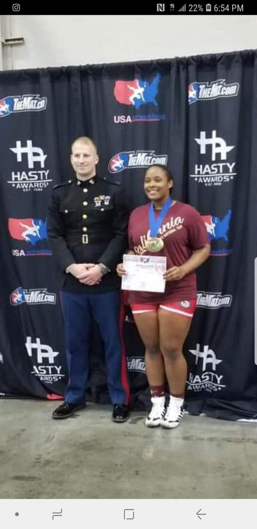 FACEBOOK PHOTOCasa Grande's Lillian McCoy, joined by a Marine Corps representative, displays the bracket that shows she won the 225-pound division at the U.S. Marine Corps Girls Folkstyle Wrestling National Championships,