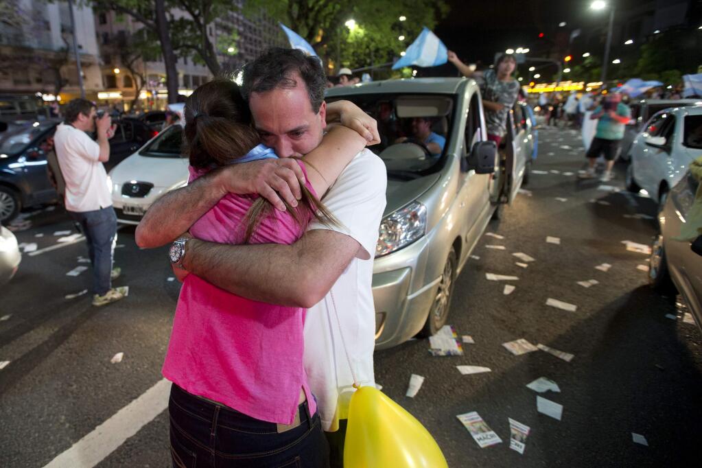 Supporters of presidential candidate Mauricio Macri hug as they celebrate in Buenos Aires, Sunday, Nov. 22, 2015. Macri won Argentina's historic runoff election against ruling party candidate Daniel Scioli, putting an end to the era of President Cristina Fernandez, who along with her late husband dominated Argentine politics for 12 years.(AP Photo/Victor R. Caivano)