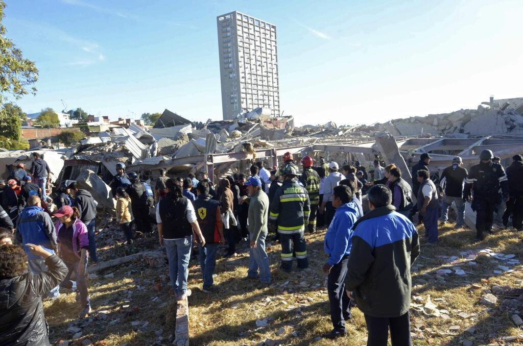 Rescue workers stand before the rubble of a children's hospital where a gas truck exploded, in Cuajimalpa on the outskirts of Mexico City, Thursday, Jan. 29, 2015. The powerful explosion shattered the hospital on the western edge of Mexico's capital, killing at least three adults and one baby and injuring dozens. (AP Photo)