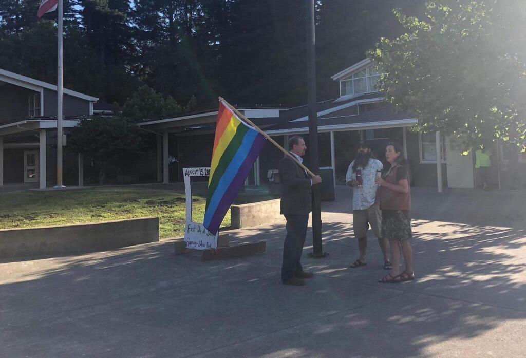 Harmony School principal-superintendent Matthew Morgan greets parents and students holding a rainbow flag. The parents with Morgan, Danielle Durfey and David Arbogast , said they support the displaying of the flag. (BRENDEN DEAN)