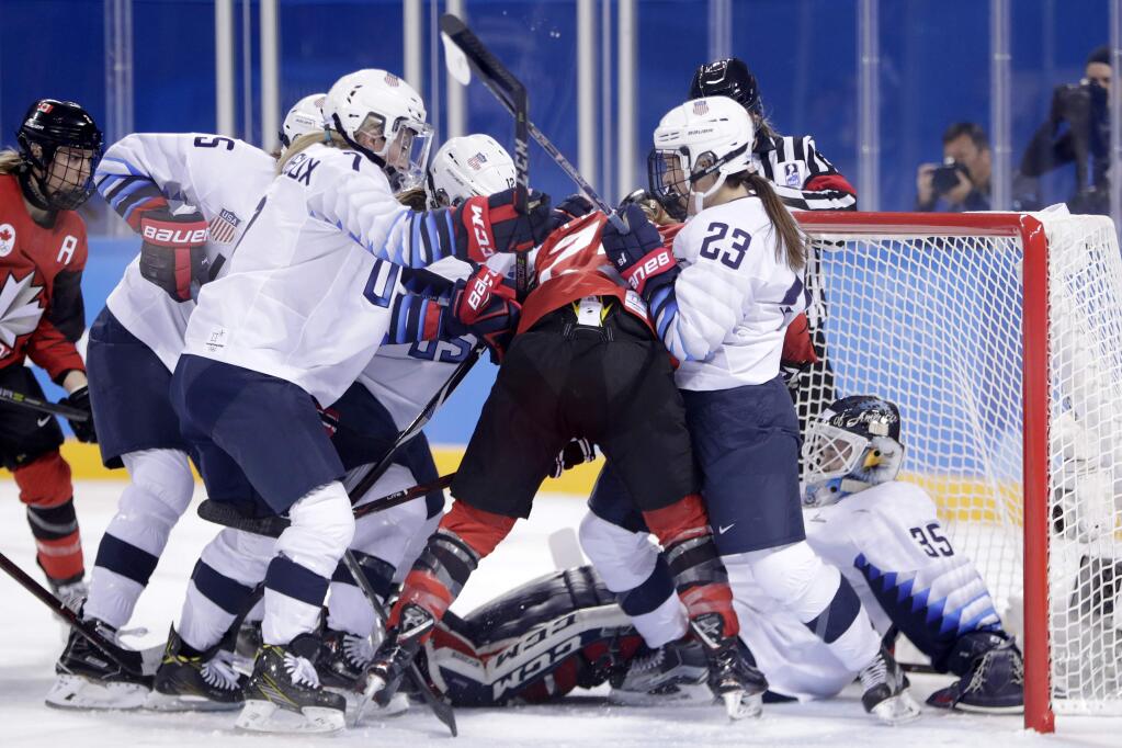 United States goalie Maddie Rooney, far right, falls into her net as teammates compete for the puck with Canada players during the first period of a preliminary round during a women's hockey game at the 2018 Winter Olympics in Gangneung, South Korea, Thursday, Feb. 15, 2018. (AP Photo/Julio Cortez)