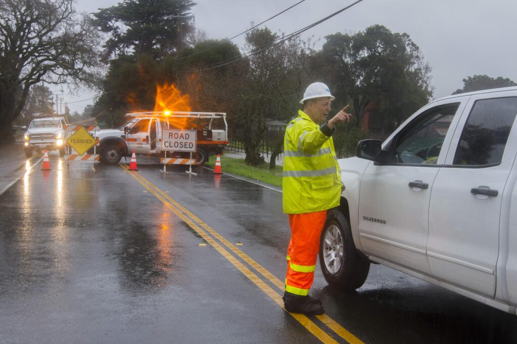 A Caltrans worker directs traffic trying to pass through the intersection of Broadway and Highway 121 as a second storm passed through Sonoma valley on Tuesday. (Photo by Robbi Pengelly/Index-Tribune)