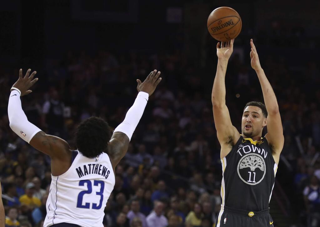 The Golden State Warriors' Klay Thompson, right, shoots over the Dallas Mavericks' Wesley Matthews during the second half Thursday, Feb. 8, 2018, in Oakland. (AP Photo/Ben Margot)