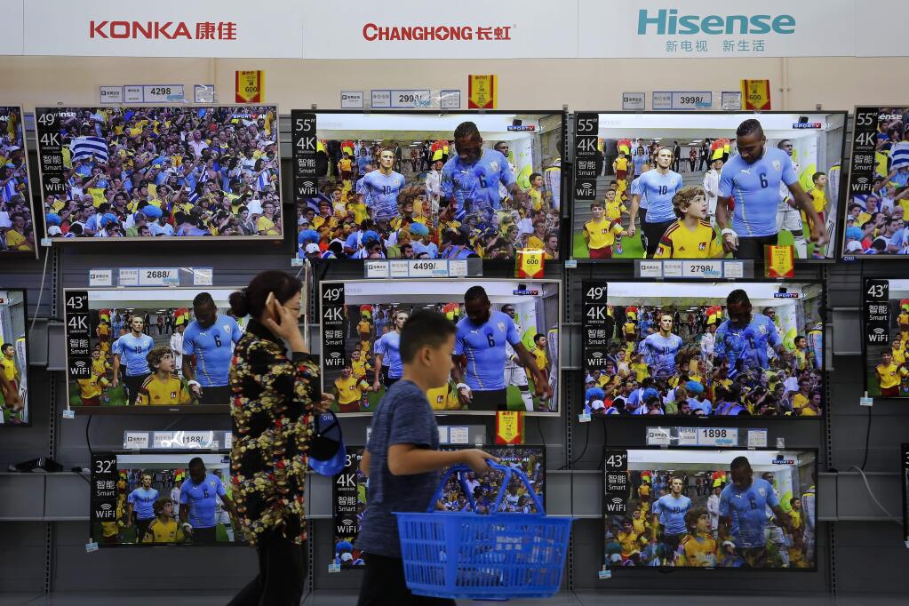 A woman and a child pass Chinese brands of flat screen TVs on display at a hypermarket in Beijing, Wednesday, July 11, 2018. China's government has criticized the latest U.S. threat of a tariff hike as 'totally unacceptable' and vowed to retaliate in their escalating trade war. The Commerce Ministry on Wednesday gave no details, but Beijing responded to last week's U.S. tariff hike on $34 billion of imports from China by increasing its own duties on the same amount of American goods. (AP Photo/Andy Wong)