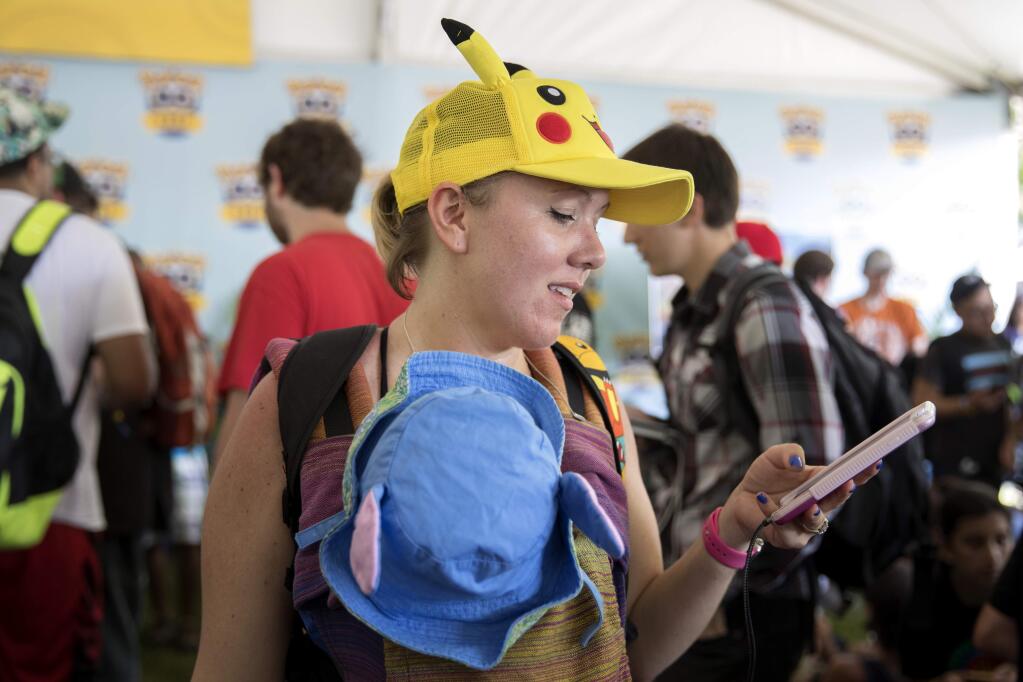 Lauren Schuster of Miami looks at her phone as she struggles to get her Pokemon Go game to quit crashing at the Pokemon Go Fest Saturday, July 22, 2017, at Grant Park in Chicago. Many festival attendees had trouble getting the augmented-reality cellphone game to work. By the afternoon, Mike Quigley, chief marketing officer of the game's developer, Niantic, announced all ticket holders would receive refunds and be issued $100 in credits for use in the app. Schuster and a group of others came to Chicago just for the event. (Erin Hooley/Chicago Tribune via AP)