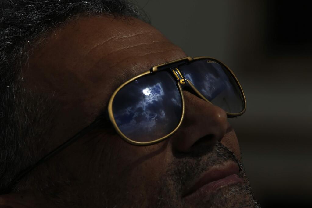 The solar eclipse is reflected on the sunglasses of a man in Nicosia, Cyprus, Friday, March 20, 2015. An eclipse is darkening parts of Europe on Friday in a rare solar event that won't be repeated for more than a decade. (AP Photo/Petros Karadjias)