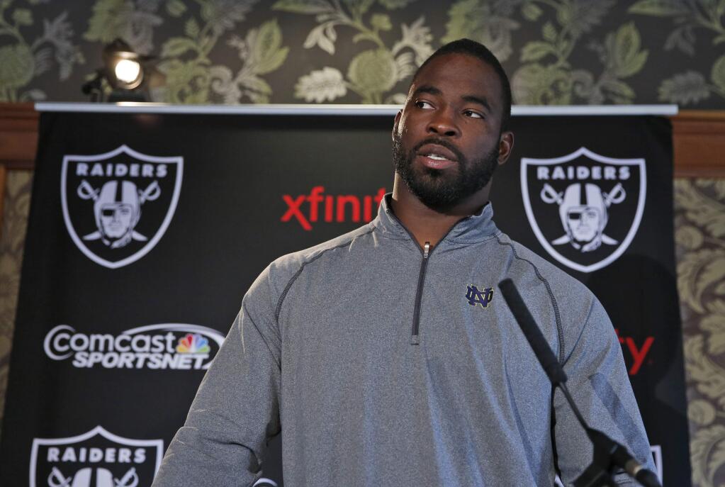 Oakland Raiders player Justin Tuck answers a reporter's question during a media conference following a training session at Pennyhill Park, Bagshot, England, Thursday, Sept. 25, 2014. (AP Photo/Lefteris Pitarakis)