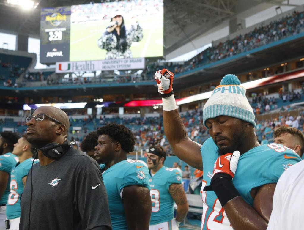 Miami Dolphins defensive end Robert Quinn raises his right fist during the singing of the national anthem, before the team'spreseason game against the Tampa Bay Buccaneers, Thursday, Aug. 9, 2018, in Miami Gardens, Fla. (AP Photo/Wilfredo Lee)