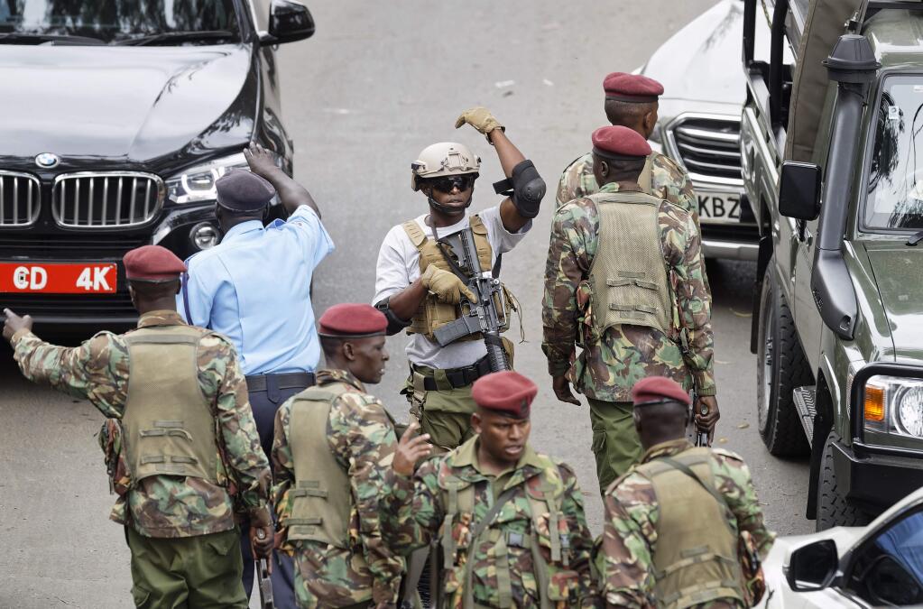 A member of Kenyan special forces, center, gestures to his colleagues to move out, at the scene of the attack Wednesday, Jan. 16, 2019 in Nairobi, Kenya. Extremists stormed a luxury hotel in Kenya's capital on Tuesday, setting off thunderous explosions and gunning down people at cafe tables in an attack claimed by Africa's deadliest Islamic militant group. (AP Photo/Ben Curtis)