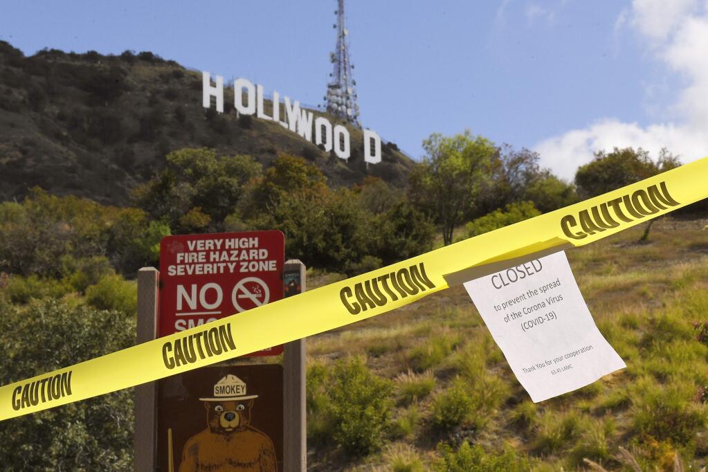 A sign is seen at the entrance to Innsdale Trail near the Hollywood Sign, Saturday, March 28, 2020, in Los Angeles. With cases of coronavirus surging and the death toll surpassing 100, lawmakers are pleading with cooped-up Californians to spend a second weekend at home to slow the spread of the infections. It has been more than a week since Gov. Gavin Newsom barred 40 million residents from going outdoors except for essentials. Even so, reports of crowds have prompted local and state officials to warn that ignoring social distancing, park and beach closures could spread the virus, which already is surging. (AP Photo/Mark J. Terrill)