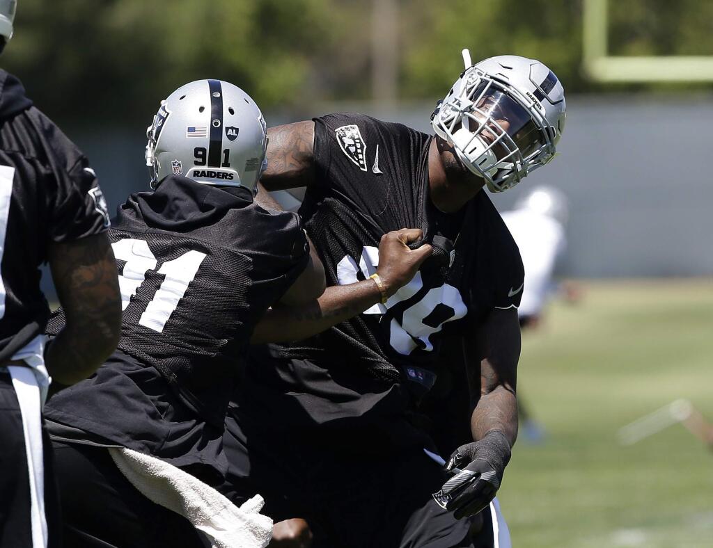 Oakland Raiders linebacker Shilique Calhoun, left, and rookie defensive end Arden Key, right, work on a drill at the team's minicamp Tuesday, June 12, 2018, in Alameda. (AP Photo/Rich Pedroncelli)