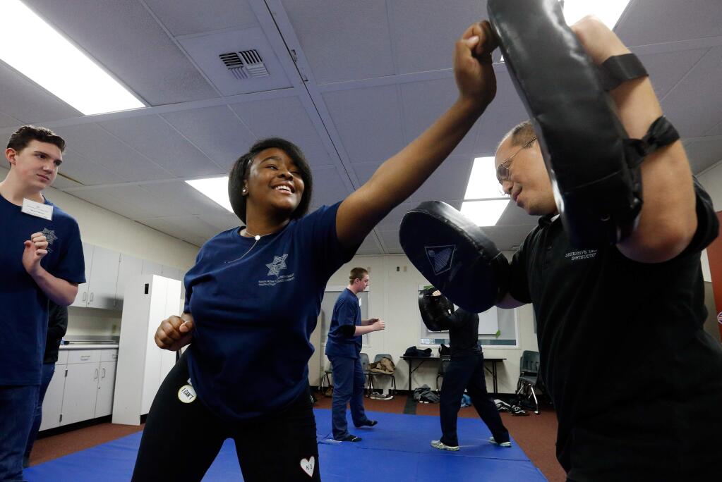 Trina Salmon, 16, center, tries out a palm heel strike with Santa Rosa police officer and defensive tactics instructor Hiroshi Yaguchi, right, during the Youth Citizen Police Academy in Santa Rosa, California on Saturday, February 4, 2017. (Alvin Jornada / The Press Democrat)