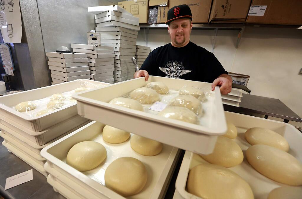 Drew Peletz stacks away extra dough in preparation for Super Bowl Sundday at Mombo's Pizza in Santa Rosa. (Photo by John Burgess/The Press Democrat)