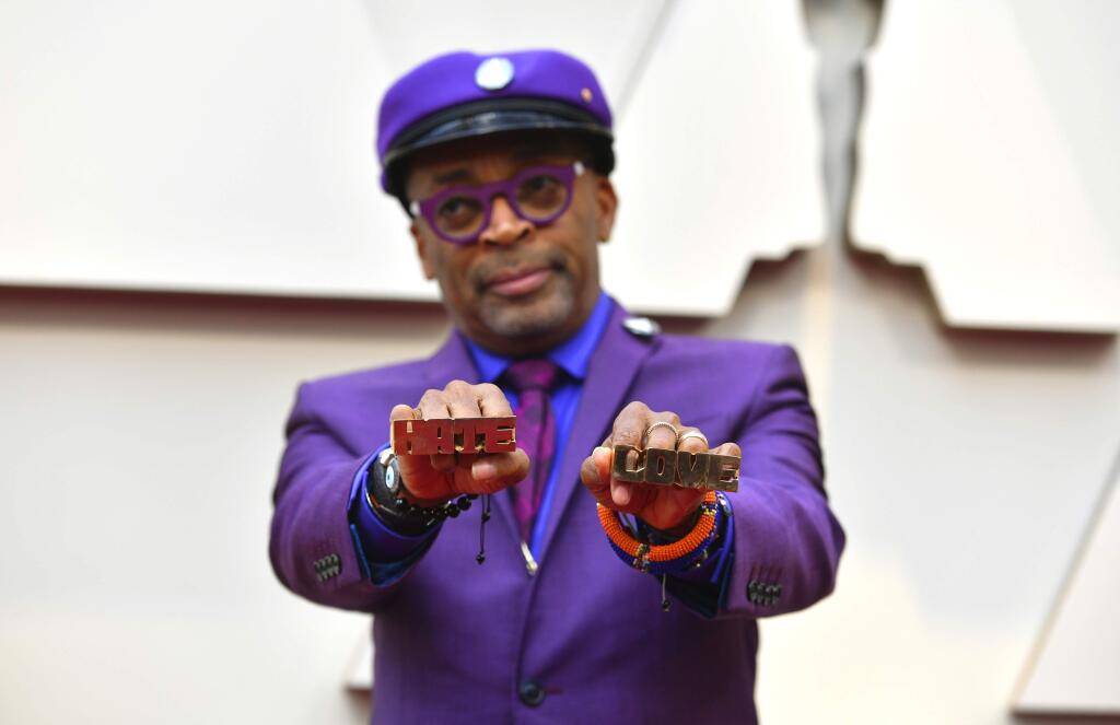 Spike Lee holds up brass knuckles reading 'hate' and 'love' from his iconic film 'Do The Right Thing' as he arrives at the Oscars on Sunday, Feb. 24, 2019, at the Dolby Theatre in Los Angeles. (Photo by Jordan Strauss/Invision/AP)