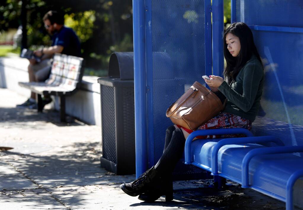 Santa Rosa Junior College student Rei Murakami waits for a Sonoma County Transit bus to Sonoma at the bus stop on Mendocino Ave. at Pacific Ave. in Santa Rosa, California on Tuesday, September 30, 2014. (BETH SCHLANKER/ The Press Democrat)
