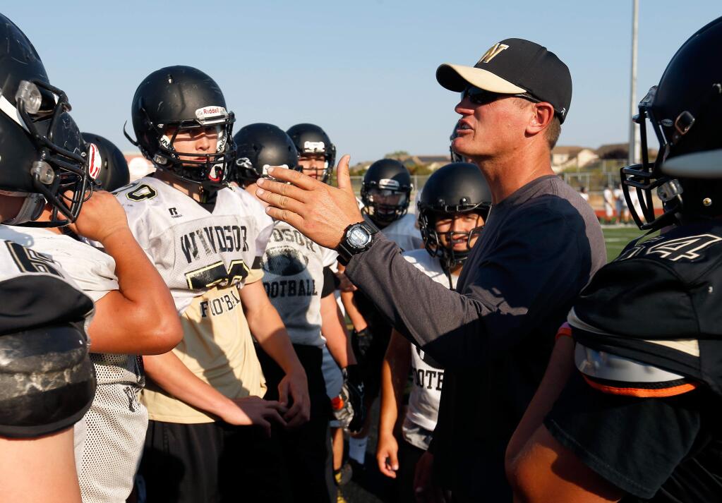 Windsor head coach Kevin Ballatore, right, huddles with his players during varsity football practice at Windsor High School, in Windsor, California on Wednesday, August 23, 2017. (Alvin Jornada / The Press Democrat)