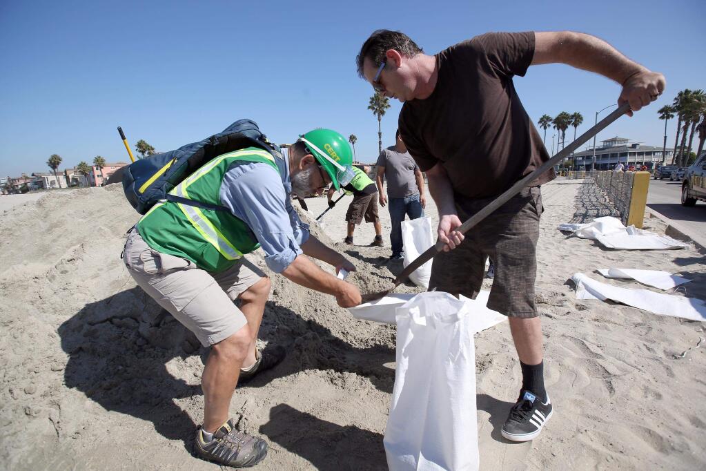 Community volunteer Edwin Schakeroh, left, helps Gavin Greely a resident fill sand bags in preparing for an expected storm surge in Long Beach, Calif., Tuesday, Aug. 26, 2014. (AP Photo/ Nick Ut )