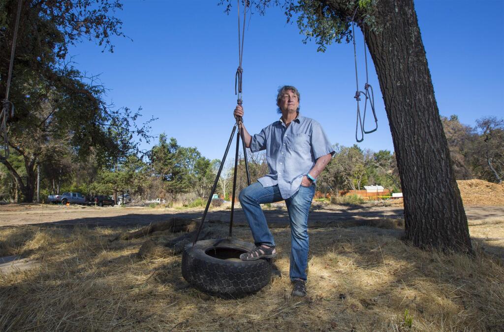 Arthur Dawson, on his Warm Springs Road property, with one of the few items to escape last October's firestorm - a tire swing used by his wife Jill's preschool students. (Photo by Robbi Pengelly/Index-Tribune)