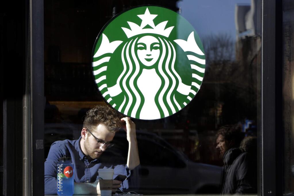 FILE - In this Jan. 11, 2016, photo, a man sits inside a Starbucks, in New York. (AP Photo/Mark Lennihan)