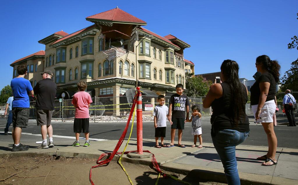 Residents and tourists take pictures in front of the damage caused by Sunday's earthquake in downtown Napa on Tuesday, Aug. 26, 2014. (Conner Jay/The Press Democrat)