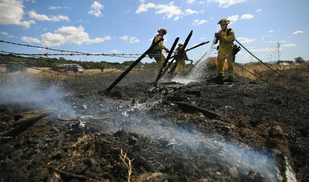 Cal Fire firefighters douse the remains of a brush fire near Rohnert Park, Thursday, Sept. 19, 2019 off Roberts Road. Despite the rain this week, fire danger will ramp up in the coming days with a forecast of warmer temperatures, low relative humidity and offshore flow. (Kent Porter / The Press Democrat